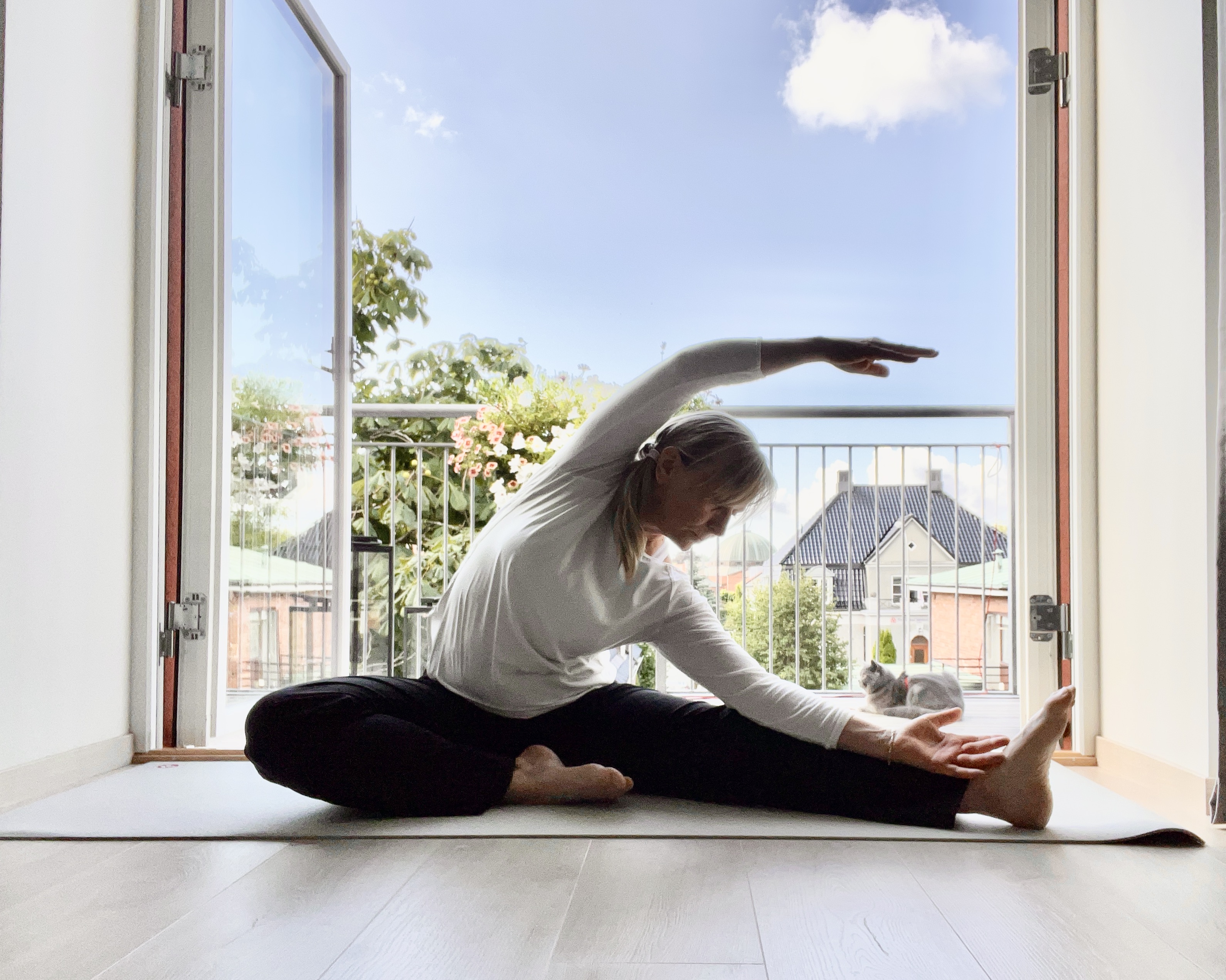 Sittende sidebøy på matte ved åpen balkongdør